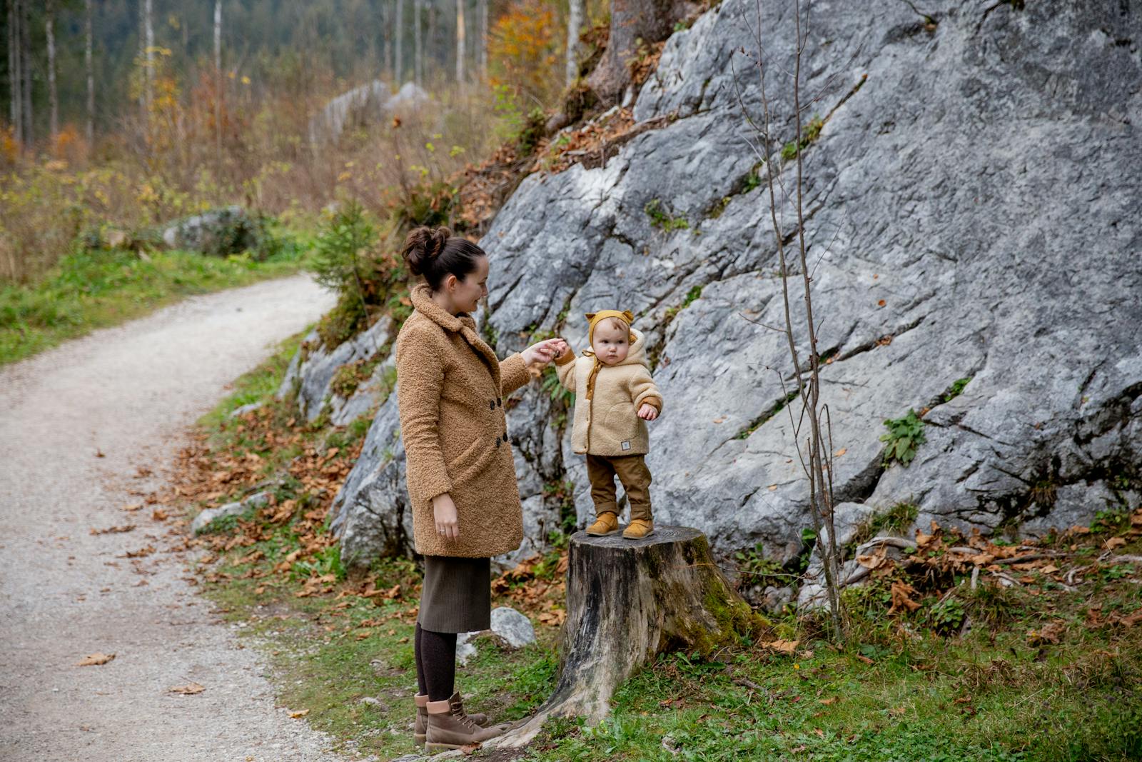 A mother and child enjoying a playful moment in an autumn forest setting.